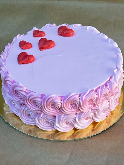 An elegant cake with pink ombre rosettes and delicate red hearts on top. A beautiful and romantic design for your special someone.
