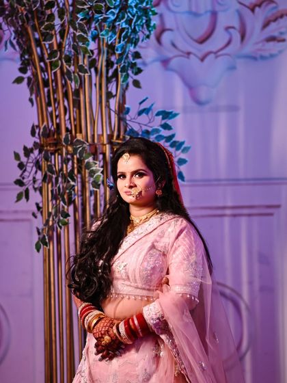 A solo portrait of the bride in her lovely pink reception lehenga. This shot captures her elegance and poise against the beautiful wedding decor.