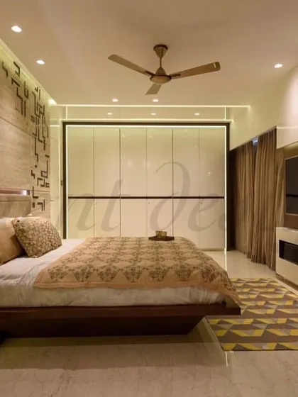 This bedroom design uses a floating bed to create a sense of spaciousness. The warm, ambient lighting from below the bed and behind the textured stone headboard adds depth and a cozy atmosphere.