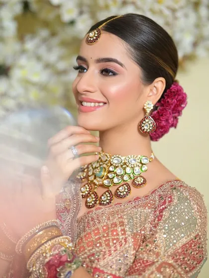 A side profile of this beautiful bride, showcasing the floral bun and the soft, glowing makeup that looks perfect against the floral backdrop.
