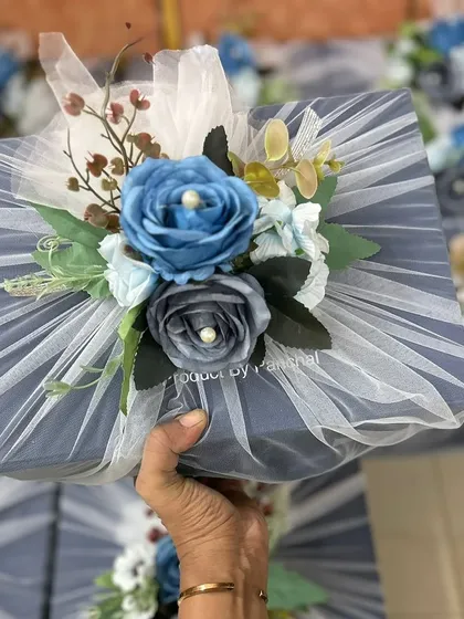 Holding up one of the elegant corporate gift boxes for ASTCL, showcasing the handcrafted floral arrangement on top.