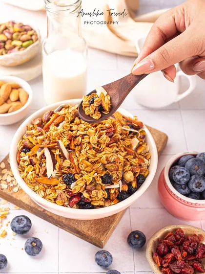 A spoonful of crunchy granola being scooped from a bowl. This action shot highlights the texture and makes the healthy breakfast look delicious and appealing.