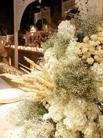 A lush arrangement of white hydrangeas, baby's breath, and dried pampas grass, adding texture to the monochromatic theme.