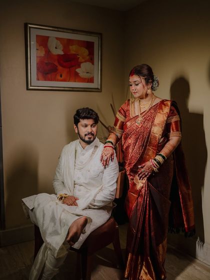 A beautifully lit indoor portrait of the couple. The bride's hand on the groom's shoulder conveys a sense of partnership and affection.