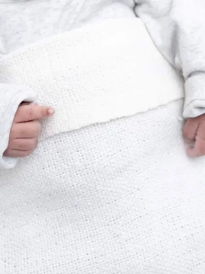 A close-up of a newborn's tiny hands, resting gently on a soft white blanket. It's all in the details, and these small features tell a big story of new life.
