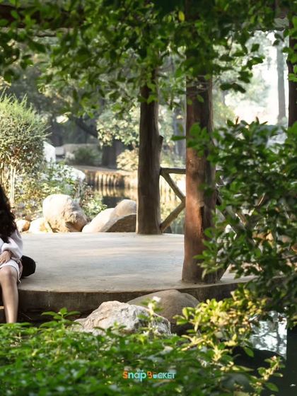Finding a quiet spot in a lush park for a relaxed portrait. This wide shot captures the beautiful scenery and the couple enjoying a peaceful moment together before their baby arrives.