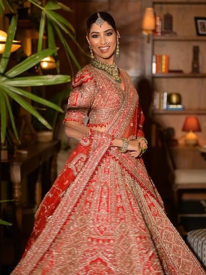 A candid, happy shot of a model in a red lehenga, showing the outfit's beautiful movement and drape.
