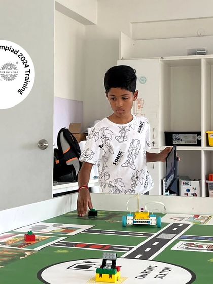 A student carefully maneuvers his robot on the IRO 2024 training mat. This individual practice is crucial for mastering the robot's controls and mission sequences.