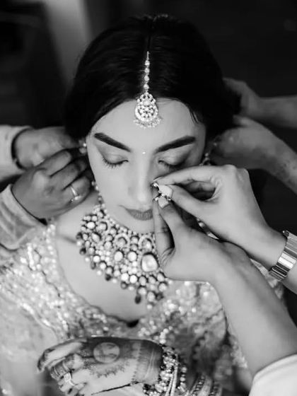A close-up black and white shot of the bride getting ready, surrounded by the hands of her loved ones. It's an intimate and powerful image about the community of support around a bride.