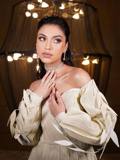 An artistic and modern look. The makeup is soft and ethereal, with a focus on a dewy complexion, complementing the unique, leaf-detailed dress.