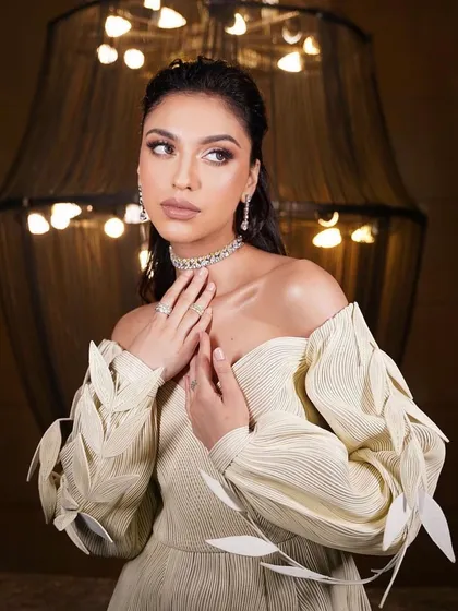 An artistic and modern look. The makeup is soft and ethereal, with a focus on a dewy complexion, complementing the unique, leaf-detailed dress.