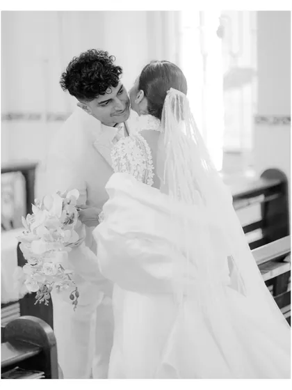 A candid black and white photograph capturing a sweet kiss on the cheek inside the church after the ceremony.