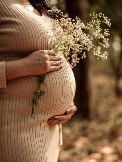 A beautiful close-up of the mom-to-be holding a delicate bouquet of baby's breath against her bump. The textures of the ribbed dress, the flowers, and her skin create a lovely composition.
