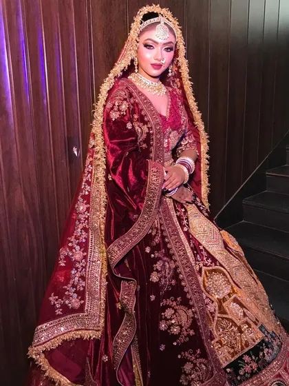 Full view of the royal maroon velvet bridal lehenga, showcasing its grand flare and the intricate patterns that cover the entire outfit.