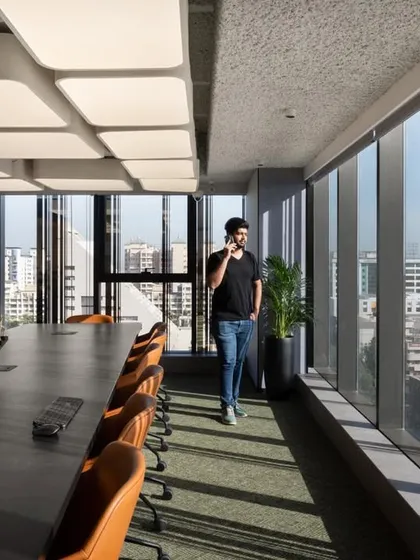 A long boardroom with floor-to-ceiling windows offering panoramic city views. The natural light and expansive view create an inspiring environment for important meetings.