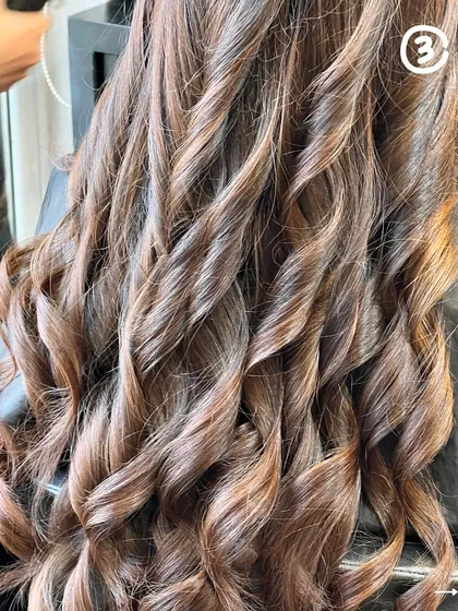 A close-up of beautifully styled barrel curls, showing off a rich, multi-tonal brown color.