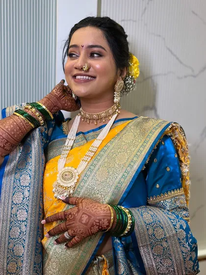 A happy, smiling bride, showing the complete look with her beautiful saree and jewelry.