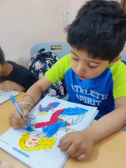 A young boy carefully coloring a picture in his book. We encourage neatness and attention to detail from an early age.