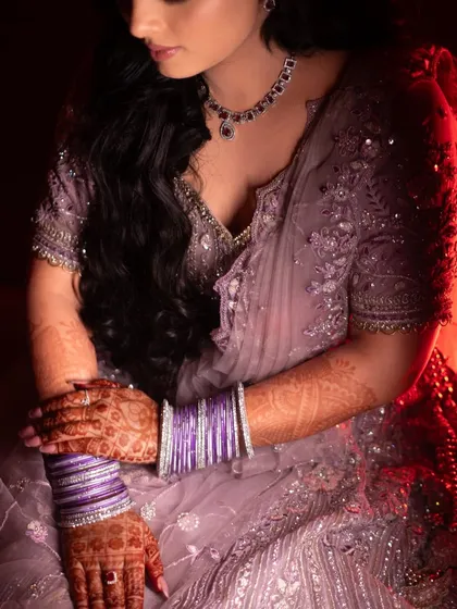 A portrait focusing on the bride's hands, adorned with mehndi and bangles, resting on her lap. This shot highlights the details and traditions of the bridal look.
