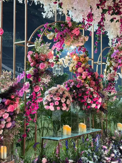 A detail of the floral-adorned golden archways. The combination of a classic chandelier with a profusion of colorful flowers creates a look of whimsical elegance.