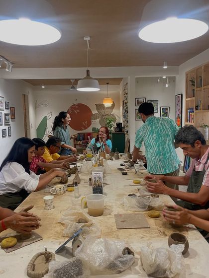 A full view of our clay workshop table, where a large group is busy molding and shaping their creations under the warm studio lights.