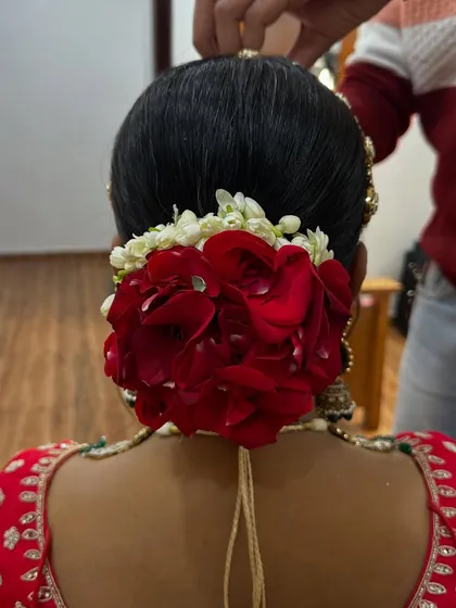 A classic bridal hairstyle. This beautiful low bun is decorated with fresh red roses and jasmine, creating a timeless and elegant look for her wedding day.