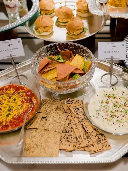 A classic party starter: a Mexican layer dip with nachos and a classic hummus with assorted crackers. These dips are always a crowd-pleaser.