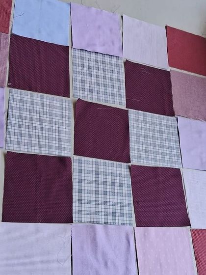 The initial layout of fabric squares for a patchwork quilt, showing the design process in its early stages.