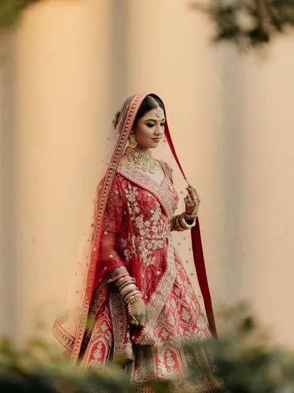 An artistic and moody shot of my bride Hershee in her red sangeet or wedding lehenga. The soft glam makeup with a focus on dewy skin looks stunning in any light.