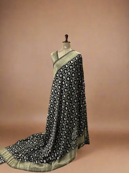 A classic black soft crepe saree with a white floral jaal and a beige border.