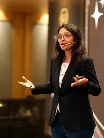 Speaking on stage in a black suit. Your job may end one day, but your book, your brand, and your impact live on. Your real promotion is becoming the author of your life.