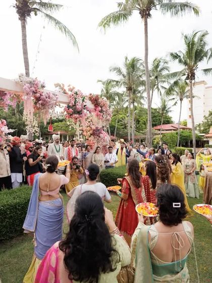 A wide shot of the beautiful outdoor groom's entry. The floral arch and palm trees made for a stunning backdrop.