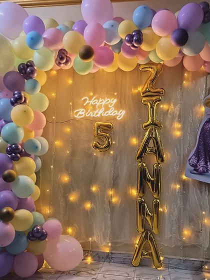 A lovely Rapunzel-themed decoration for a 5th birthday. The pastel balloon arch, fairy lights, and character cutout create a magical setting.