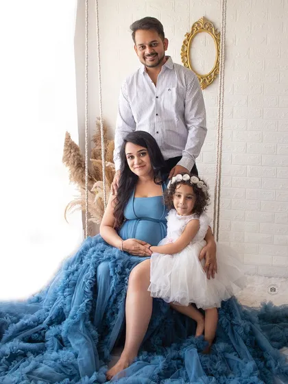 A beautiful family portrait during a maternity session. The flowing blue dress and the daughter's sweet presence make this a picture-perfect moment.