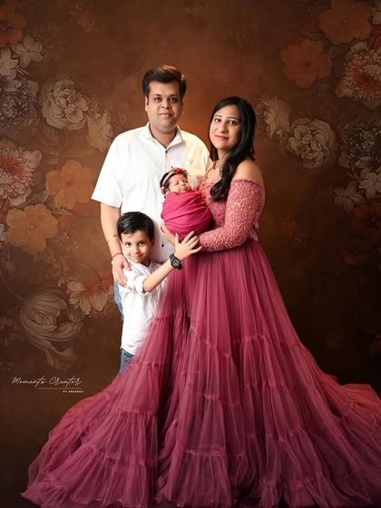 A complete family portrait with their new baby girl. The big brother stands proudly beside his parents, creating a lovely memory of their new family of four.
