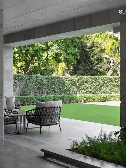 A covered walkway at the entrance provides a seamless transition from the outdoors, with views into the lush side lawn, blurring the lines between the home and its landscape.