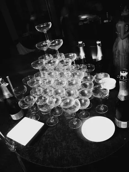 An artistic, grainy black and white shot of the champagne tower post-celebration. It has a moody, after-party feel, capturing the remnants of a great night.
