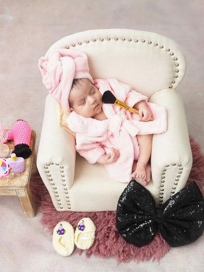 A spa day for the little diva. This fun and girly setup features a newborn in a pink robe and towel, ready for some pampering.