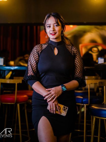 A guest in a black dress with mesh sleeves.