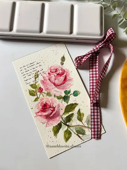A close-up of a vintage-style floral card painted with soft pink watercolor roses. I added some script text in the background and a gingham ribbon to complete the romantic look.