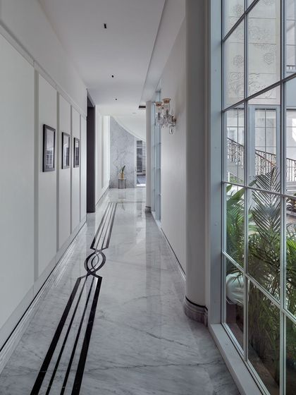 This view highlights the exquisite details of the corridor, with its intricate black and white marble inlay flooring and classic wall paneling. Every element is designed to guide the eye and create a sense of elegant, flowing movement through the home.