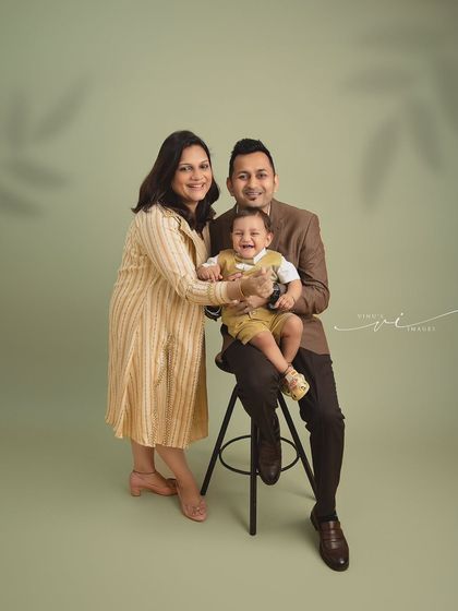 A picture of a happy family. This studio portrait shows the parents doting on their giggling baby, creating a memory of pure joy and togetherness.