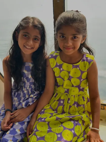 A sweet moment between two friends in their matching printed cotton dresses. The designs are bright, cheerful, and made for comfort.