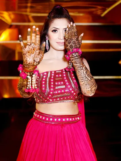 A playful pose showing both the front and back of the bride's hands, covered in beautiful Mehndi.