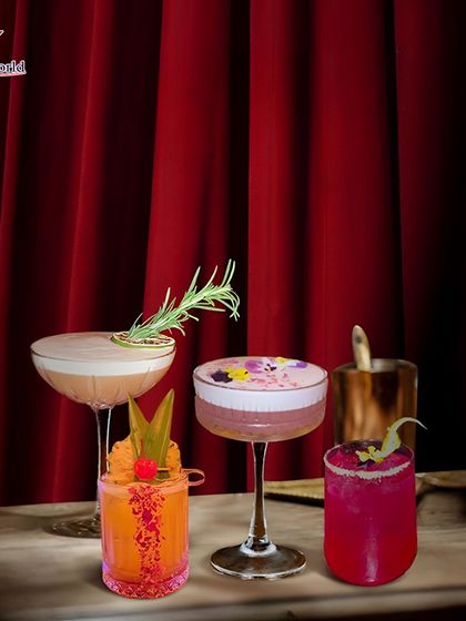 A beautiful lineup of our handcrafted mocktails and cocktails against a dramatic red curtain. This image shows our range, from creamy sours to vibrant, fruity creations, all presented with artistic flair.