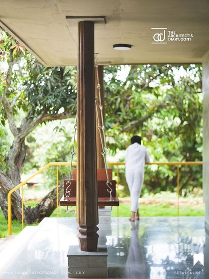 A view from the verandah, where life unfolds in harmony with nature. The traditional swing, supported by a classic wooden pillar, offers a place for quiet reflection, overlooking the mango grove.