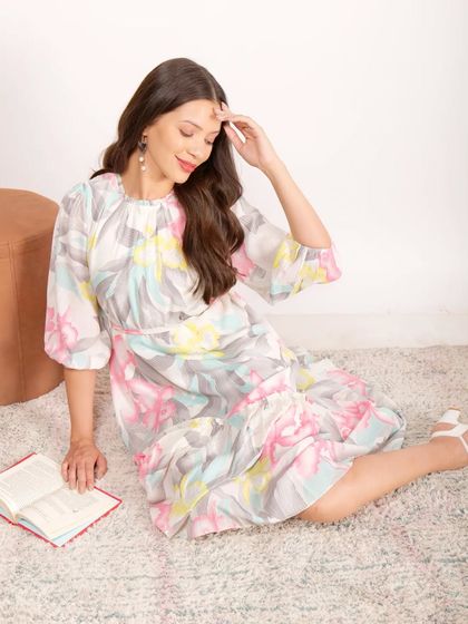 A model in a floral dress seated on a rug with a book, creating a soft, lifestyle-inspired scene within the studio.
