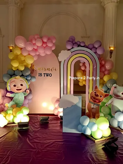 A pastel rainbow Cocomelon theme for a second birthday. This decoration includes a double rainbow arch, character cutouts, and a balloon mosaic number, creating a soft and dreamy party atmosphere.