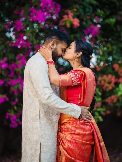 A sweet kiss against a vibrant wall of flowers. This intimate moment from Devika and Laukik's engagement is full of color and romance.