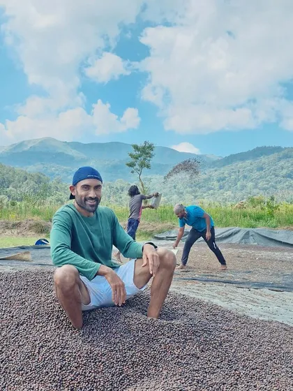 This is what hands-on looks like. I'm sitting on a fresh pile of our Robusta coffee beans as they begin the drying process, a critical step in developing their flavor. You can see the hard work happening right here, with the mountains as our constant backdrop.